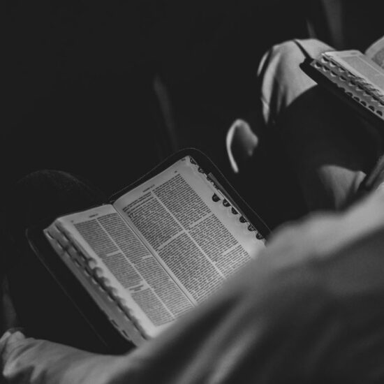 monochrome image of open bible being read